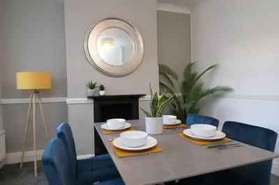 a dining room table with blue chairs and a mirror at Lancaster 2 Bedroom Characterful House - with Wifi in Lancaster