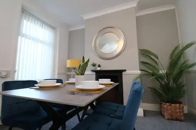 a dining room table with blue chairs and a mirror at Lancaster 2 Bedroom Characterful House - with Wifi in Lancaster