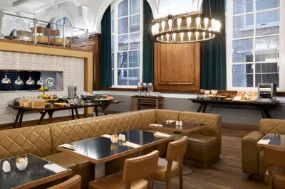 a restaurant with tables and chairs and a fireplace at Aloft Liverpool in Liverpool