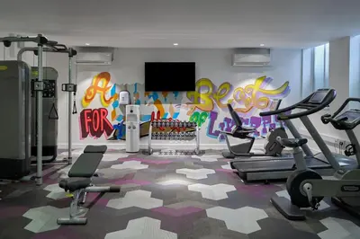 a gym with exercise equipment and a wall with graffiti at Aloft Liverpool in Liverpool