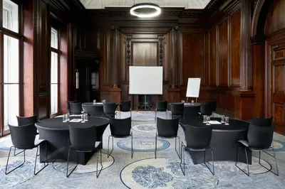 a room with tables and chairs and a projection screen at Aloft Liverpool in Liverpool