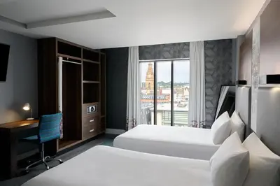 a hotel room with two beds and a desk and a window at Aloft Liverpool in Liverpool