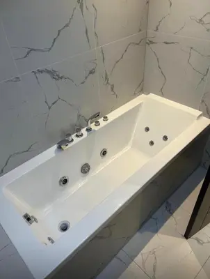a white bath tub in a bathroom with marble walls at Philharmonic Hotel in Liverpool