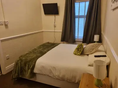 a bedroom with a large bed with a window at Lexham Apartments in Blackpool