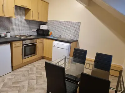 a kitchen with white appliances and black counter tops at Lexham Apartments in Blackpool