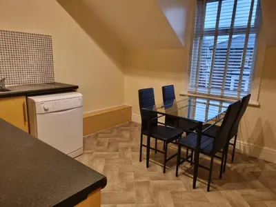 a small kitchen with a glass table and chairs at Lexham Apartments in Blackpool