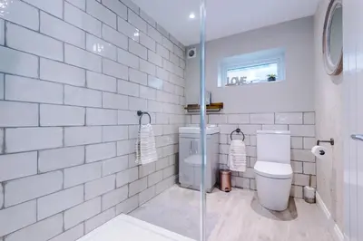a white tiled bathroom with a toilet and a shower at The Knoll Lodge- Beautiful Luxurious One Double Bedroom Property in Farington