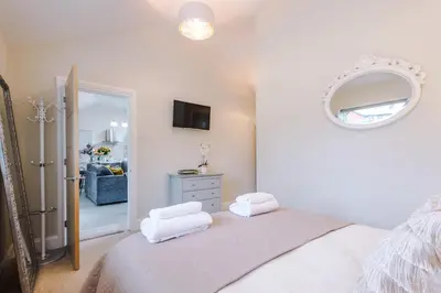 a bedroom with a bed with white sheets and a mirror at The Knoll Lodge- Beautiful Luxurious One Double Bedroom Property in Farington