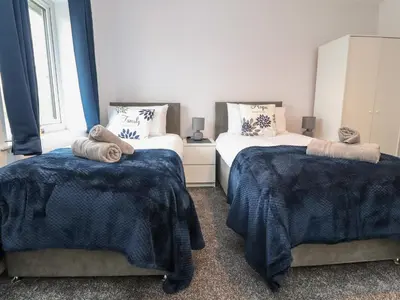 a bedroom with two beds with blue and white blankets at 3 Thrimby Court in Morecambe