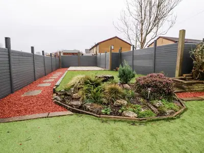 a backyard with a fence and a garden with plants at 3 Thrimby Court in Morecambe