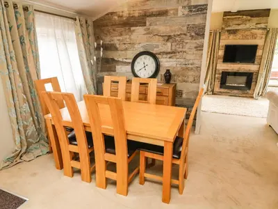 a dining room table and chairs with a clock on a wall at Lakeside 12 in Carnforth