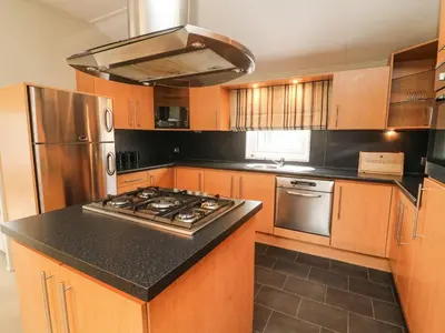 a kitchen with wooden cabinets and a stove top oven at Lakeside 12 in Carnforth