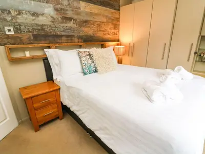 a bedroom with a white bed with a wooden headboard at Lakeside 12 in Carnforth