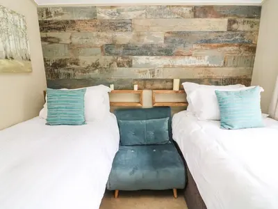 a bedroom with two beds and a blue chair at Lakeside 12 in Carnforth