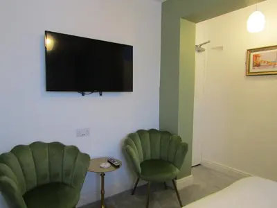 a room with two green chairs and a flat screen tv at The Scala Hotel in Blackpool