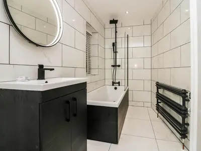 a bathroom with a sink and a tub and a mirror at Eden on the Crescent in Morecambe