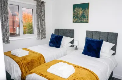 two beds in a white room with blue pillows at The Oasis - For Contractors and Individuals in Wigan