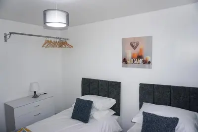 a bedroom with two beds with white sheets and blue pillows at The Oasis - For Contractors and Individuals in Wigan