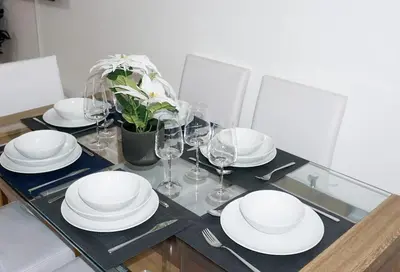 a dining table with white plates and wine glasses at The Oasis - For Contractors and Individuals in Wigan