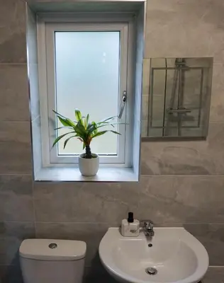 a bathroom with a toilet and a sink and a window at The Oasis - For Contractors and Individuals in Wigan