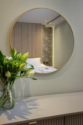 a mirror on a wall above a table with a vase at Signature Apartments in Blackpool
