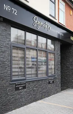 a store front of a brick building with windows at Signature Apartments in Blackpool