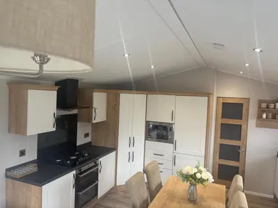 a kitchen with white cabinets and a table with flowers at 8 lakeview in Clitheroe