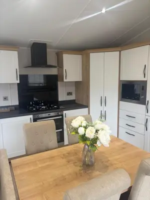 a kitchen with a table with a vase of flowers on it at 8 lakeview in Clitheroe