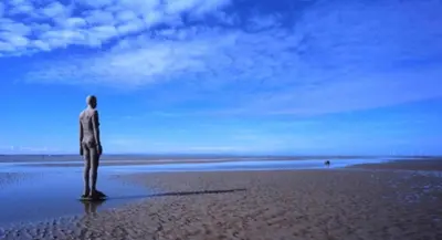a man standing on a beach looking at the ocean at Lovely 2 bed apartment in Crosby in Liverpool