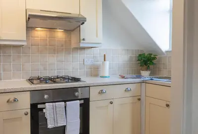 a kitchen with white cabinets and a stove top oven at Stonyhurst Spacious apartment, great location. in Clitheroe