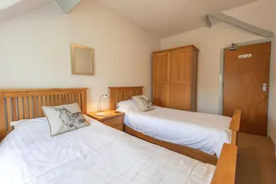 a bedroom with two beds and a night stand with a lamp at Stonyhurst Spacious apartment, great location. in Clitheroe