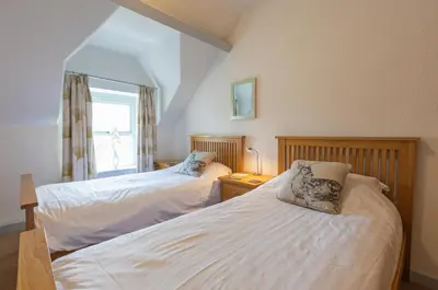 two beds in a room with a window at Stonyhurst Spacious apartment, great location. in Clitheroe