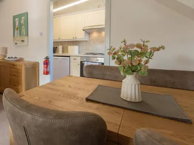 a vase of flowers on a wooden table in a kitchen at Stonyhurst Spacious apartment, great location. in Clitheroe