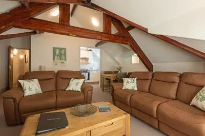 a living room with brown leather couches and a table at Stonyhurst Spacious apartment, great location. in Clitheroe