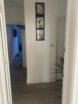 a hallway with three pictures on a white wall at Holiday Plus - Palatine Road in Blackpool