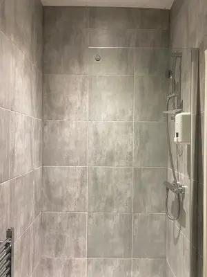 a bathroom with a shower with a tiled wall at Holiday Plus - Palatine Road in Blackpool
