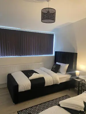 a bedroom with two beds and a chandelier at Holiday Plus - Palatine Road in Blackpool