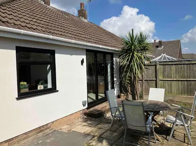 a patio with a table and chairs next to a house at Newly renovated, modern bungalow - quiet location in Lytham St Annes