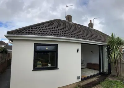 a white house with a black roof and a window at Newly renovated, modern bungalow - quiet location in Lytham St Annes