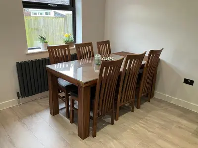 a dining room table with wooden chairs and a table and a window at Newly renovated, modern bungalow - quiet location in Lytham St Annes
