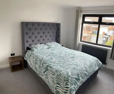 a bedroom with a bed with a blue and white comforter at Newly renovated, modern bungalow - quiet location in Lytham St Annes
