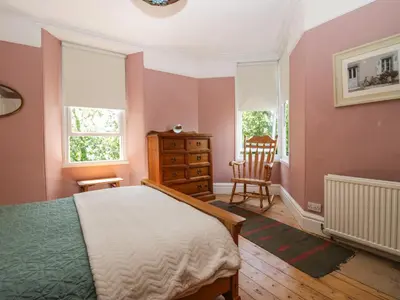 a bedroom with pink walls and a bed and a chair at Sunnycote in Carnforth