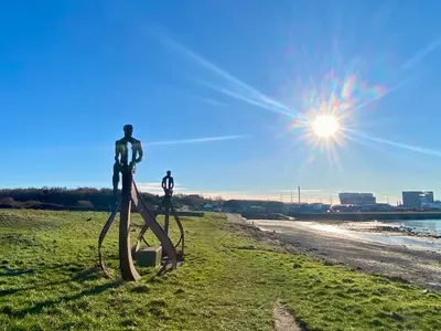 a metal sculpture on a beach with the sun in the background at Eden Stay in Morecambe