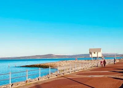 a group of people walking on a pier next to the water at Eden Stay in Morecambe