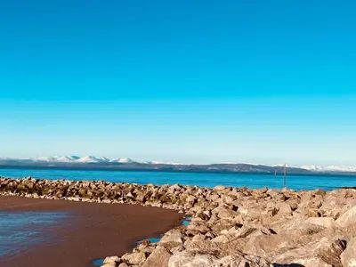 a rocky beach with the ocean and mountains in the background at Eden Stay in Morecambe