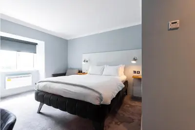 a bedroom with a large bed with white sheets at Village Hotel Blackpool in Blackpool