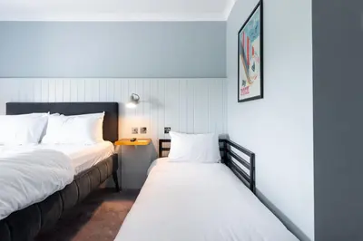 a bedroom with two beds and a desk in it at Village Hotel Blackpool in Blackpool