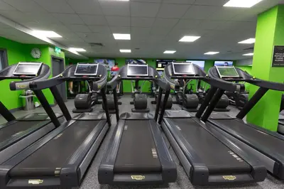 a row of treadmills in a gym with green walls at Village Hotel Blackpool in Blackpool