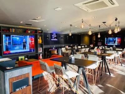 a restaurant with tables and chairs and a large screen at Village Hotel Blackpool in Blackpool