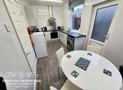 a kitchen with a white table and chairs in a room at 8 Suffolk street by Prestige Properties SA in Barrow in Furness